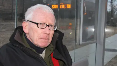 John in the bus stop opposite the embassy.