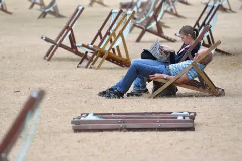 Toby Melville/ Reuters A couple relax on deckchairs on parched grass in Hyde Park in London.