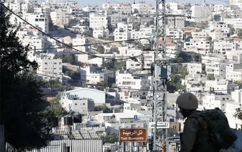 Getty Images An Israeli soldier stands guard at the entrance to a Jewish settlers zone in Hebron, 2016