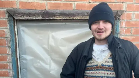 Insulate Ukraine Harry Blakiston Houston standing in front of one if his windows