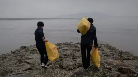 ED JONES North Korean defector activists carry bags of bottles containing rice, money, and USB sticks, on Ganghwa island, west of Seoul on May 1, 2018.