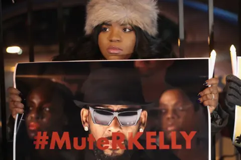 Getty Images A protester calls for Spotify and radio stations to mute R Kelly