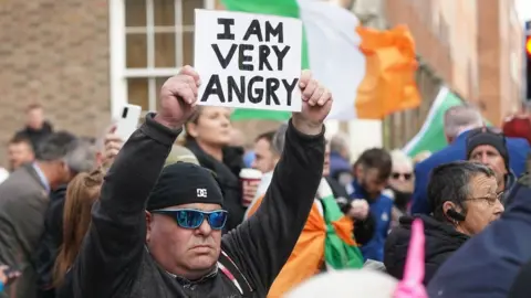 Brian Lawless/PA Man holds sign up saying "I am very angry"