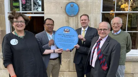 Steve Hubbard/BBC The new plaque being held by officials
