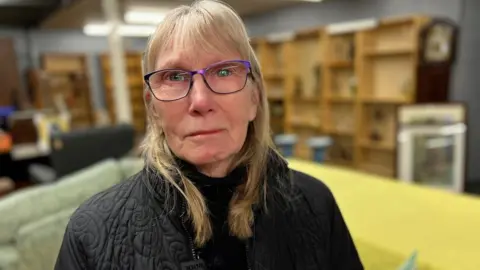 Ann Forbes looking at the camera, she is blonde and wearing glasses