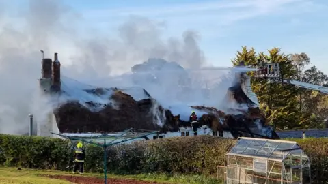 BBC Firefighers tackling thatched roof blaze