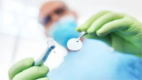 Getty Images Dentist holding instruments