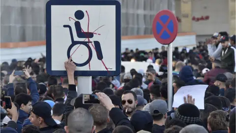 AFP Protesters put a red cross through a wheelchair access sign in Algiers, Algeria