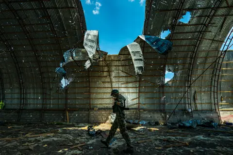 Celestino Arce / Getty Images A Ukrainian soldier walks inside a barn destroyed by Russian shelling near the frontline of the Zaporizhzhia province