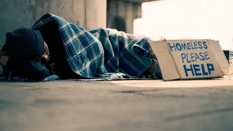 Stock image of homeless man lying on ground