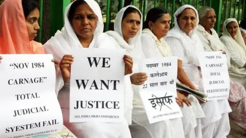 AFP/Getty Images Relatives of victims of the 1984 riots hold placards demanding justice during a rally in Delhi, India. Photo: October 2018