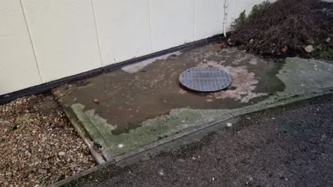 Rebecca A manhole cover with sewage leaking from underneath