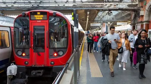 Transport for London People using mobile on the Tube platform