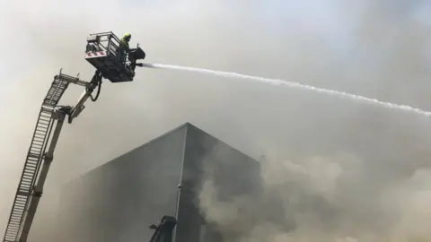 Devon and Somerset Fire and Rescue Service Firefighter blasts water from a cherry-picker