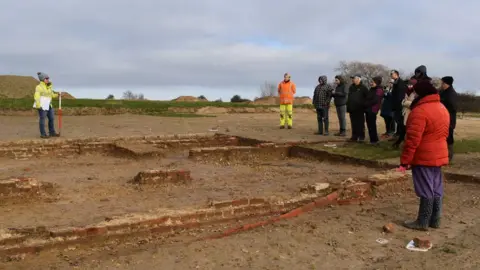 Oxford Archaeology East Ltd Archaeologists show a tour group the most well preserved building on site