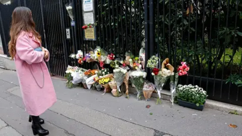 AFP A woman looks at flowers displayed outside the building where a 12-year-old schoolgirl Lola lived and who was murdered on October 18, 2022 in Paris, France