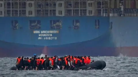 PA Media A group of people thought to be migrants crossing the Channel in a small boat traveling from the coast of France and heading in the direction of Dover, Kent