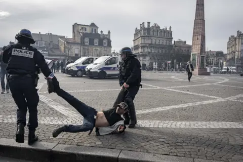 Fabien Pallueau/NurPhoto/REX/Shutterstock Riot police arrest a person during the demonstration against pension reform took place in Bordeaux on Thursday, March 23, 2022. There were several clashes between the demonstrators and the police, and at the end of the demonstration, trash fires were set