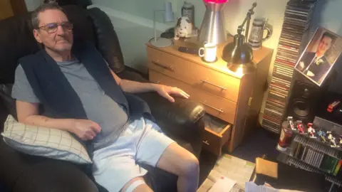 BBC Terry Lubbock at home with a photo of his son