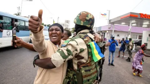 Getty Images A joyful Gabonese woman embracing a soldier of the Republican Guard