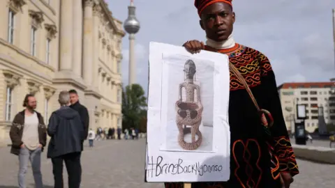 Getty Images A protester from Cameroon seeking the return of the Ngonnso statue stands outside the Humboldt Forum
