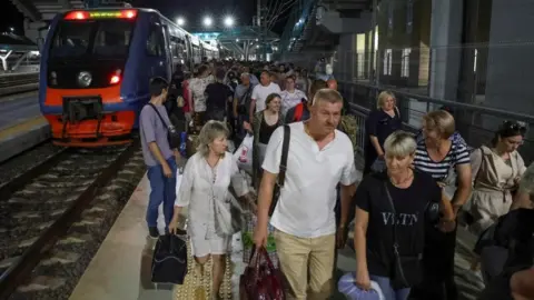 Rex Features Passengers walk out of a train, which arrived on the Crimean bridge connecting the Russian mainland with the peninsula across the Kerch Strait, to the railway station in the town of Kerch, Crimea, July 17, 2023.