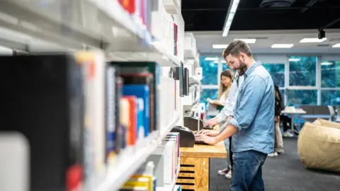 Getty Images People looking at books on the shelf of a library