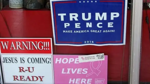 Shop window with Trump signs, a Mickey Mouse figure and an image of the Pope