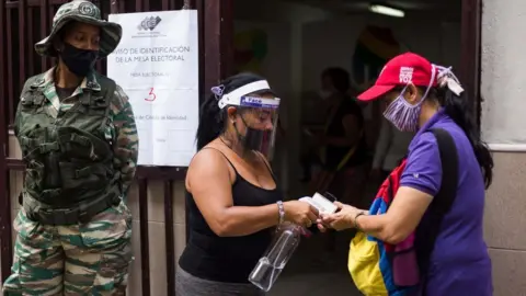Getty Images Woman having hand sanitiser applied at an election registration station in Venezuela