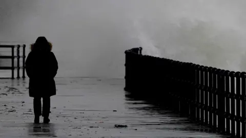 PA Media Waves crash over the promenade during rain and strong winds in Folkestone, Kent