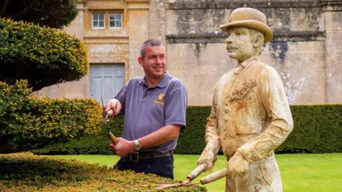 Longleat Longleat's head gardener stands next to a statue of his predecessor from 1902