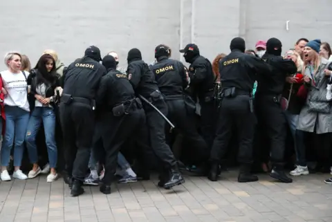 Getty Images Riot police grab people in order to detain them, from a crowd of women on 8 September