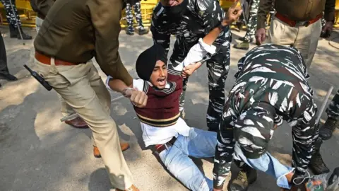 Getty Images Policemen detain a member of National Students' Union of India (NSUI) during a nationwide protest in New Delhi on February 6, 2023, calling for an inquiry into allegations of major accounting fraud at Adani, the country's biggest conglomerate.