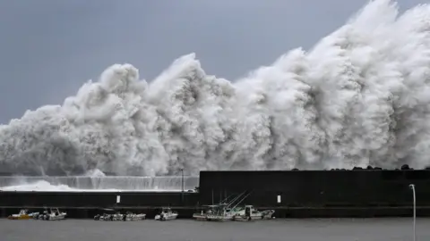 Kyodo/via REUTERS Huge waves crash into coastline