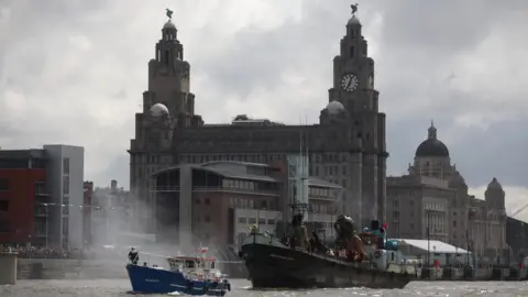 Getty Images The giant deep sea diver, the little giant girl and her dog Xolo sail along the River Mersey