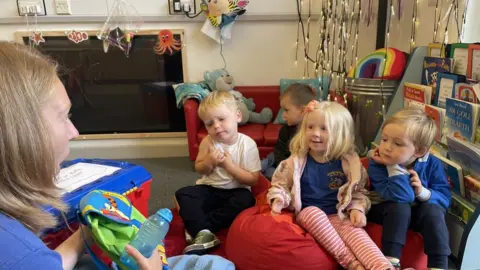 Anwen and classmates sat on beanbags at nursery while teacher sits to the left telling them about primary school