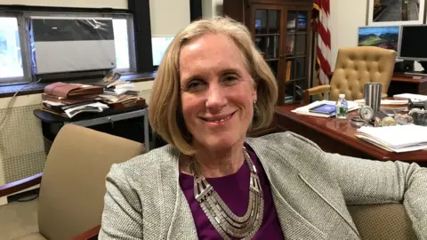 New York City Special Narcotics Prosecutor Bridget Brennan, shown in her office (she is sitting down and smiling)