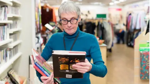 Phil Kirk/Oxfam Oxfam volunteer Janet sorts books at Wimbledon shop