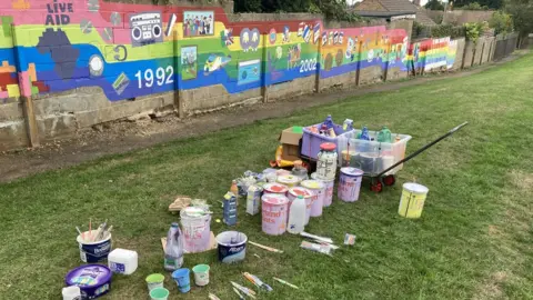 Paint pots beside mural in Hardingstone