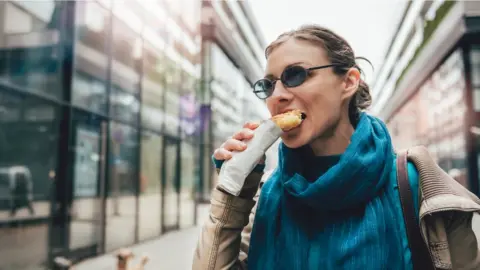 Getty Images Woman eating a snack on the go