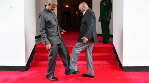 Tanzanian presidency Tanzanian President John Magufuli (R) greets Tanzanian opposition politician Maalim Seif Sharif Hamad (L) by tapping his feet against theirs to avoid themselves from coronavirus in Zanzibar, Tanzania on March 03, 2020