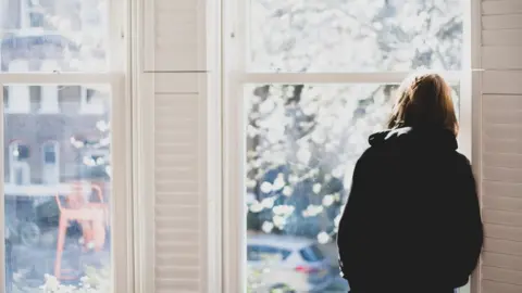 Getty Images Woman staring out of a window