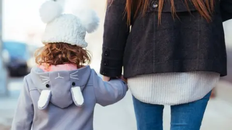 Getty Images A woman holds her daughter's hand