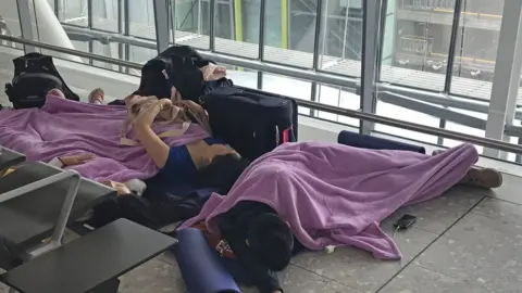 PA Media People resting in Terminal 5 at Heathrow airport