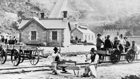 Hulton Archive Photo of quarrymen cutting slate and using a pedal-powered truck at Llanberis around 1880