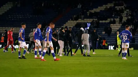 PA Media Supporters invading the pitch at Oldham Athletic