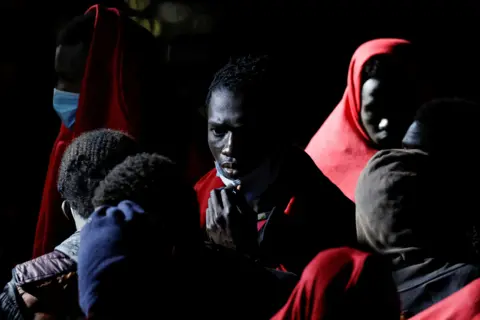 BORJA SUAREZ/Reuters Migrants wait to disembark from a Spanish coast guard vessel, in the port of Arguineguin, at the island of Gran Canaria, Spain, May 25, 2023.