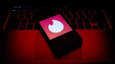 Getty Images A mobile phone showing the Tinder logo sits on a laptop keyboard.