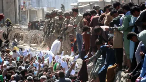 EPA Afghans struggle to reach the foreign forces to show their credentials to flee the country outside the Hamid Karzai International Airport, in Kabul, Afghanistan, 26 August 2021.