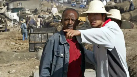 Getty Images A Chinese construction worker (R) supervises the building of a road in Addis Ababa, 27 April 2007